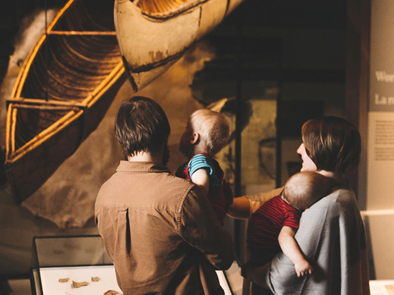 A family looks at an exhibit in the Human History Hall.