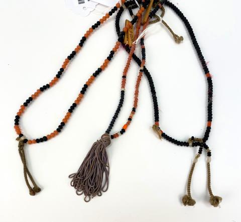 Three black and orange beaded necklaces lay on a table. 